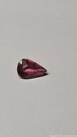 Single natural pear cut bubblegum pink tourmaline displayed on plain background, showing shape and color.