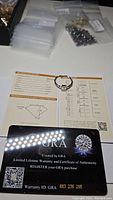 Photo of ring with GRA certification card and dossier, showing stone specs and warranty ID.