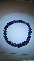 Photo of natural deep blue Lapis Lazuli bead bracelet arranged in a circle, showing smooth polished beads and vibrant blue color.