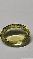 Close-up front view of oval cut lemon citrine gemstone showing color and faceting.