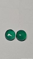 Two vivid lime green round onyx cabochon gemstones on a plain background, showing smooth polished surface and color.