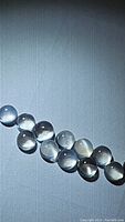Row of 11 calibrated round white moonstone cabochons showing translucency and flash