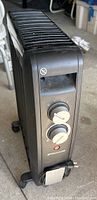 Front angled view of the black portable Bonaire heater showing the vented top and two white rotary control knobs on the front panel, with wheels at the base.