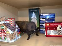 Photo showing large Yule log candle on black metal stand, ceramic gingerbread house candle holder, four boxes of Noma LED Christmas lights, and boxed replacement bulbs.