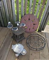 Full view of all items on deck including cast iron candle lantern, plastic sun ornament, planter holder, turtle figurine, and solar lights