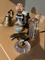 Full lot on display showing Titanic bell, ceramic figurine, black cross, butterfly, glass pen holder, and cordless phone