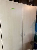 Front of large wooden storage cabinet with two closed doors and silver handles.