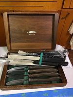 Wooden box lid open against cabinetry, Cutco logo visible on inside of lid