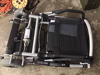 Folded view of wheelchair showing frame, seat, and footrest