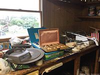 Photo of the garage workspace with shelves holding boxes and tools including a compartment box with assorted brass fittings and various other toolboxes and parts