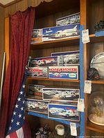 Photo of shelf stocked with multiple boxed Hess trucks and vehicles with visible winter holiday themed packaging, tagged for lot inventory