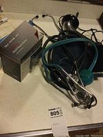 Photo showing all items including boxed blood pressure monitor, stethoscopes, Lumiscope, and cuffs on kitchen counter.