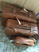 Photo of three brown leather suitcases stacked, showing the set and condition