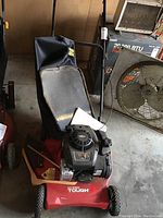 Full view of the 21-inch Hyper Tough rotary mower showing red body, black engine, handle, and grass collection bag.