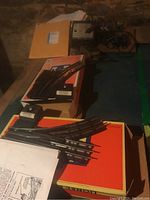 Photo showing three Lionel model train track switches resting on orange Lionel boxes, each with a black control box and metal rails.