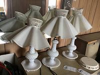Group photo showing three matching milk glass lamps with white plastic shades of varying heights arranged together.