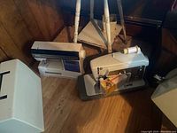 Three sewing machines on floor including a Viking by Husqvarna, a Singer Touch and Sew, and a Singer machine