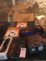 Photo showing boxed Life-Like Evergreen Trees, multiple street lamps, and additional accessories in bins