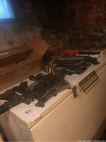 Wide view of multiple Lionel train track sections including straight and curved pieces spread on a white surface with a cardboard box in background