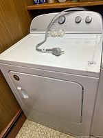 Front view of white Whirlpool electric dryer with closed door; power cord on top.