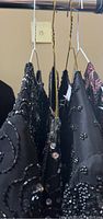 Side angle showing black and dark beaded dress tops on hangers with visible bead details and sequins.