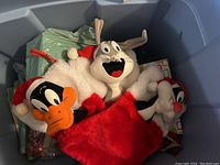 Three small Christmas stockings featuring Looney Tunes characters: Daffy Duck, Bugs Bunny, and Sylvester, in a blue storage bin.