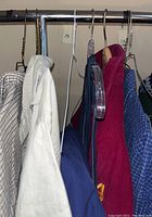 Front view of hanging vintage shirts and coats clothing on rack including corduroy coats and checked shirts.