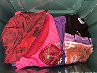 Photo showing red and black patterned wind pants, pink garment, purple and black T-shirts, small red leather bag and keychain