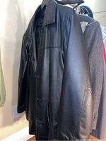 Black leather jacket hanging on rack, showing smooth surface and buttons