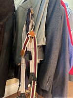 Photo of three pairs of suspenders hanging on a rack with jackets