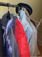 Two jackets and two vests hanging on rack, including a medium blue lined jacket and a small red fleece vest.