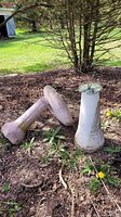 Photo of two items on soil: a ceramic bird bath and tall ceramic bird feeder without the sun dial top.