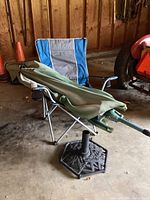 Camp chair with umbrella placed folded on top and metal umbrella stand beneath