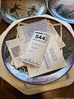 Overview image of multiple collector's plates showing floral and hummingbird designs with paperwork and styrofoam packaging.