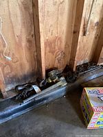 Two metal come-alongs with chains against a wooden wall, showing their condition and attached chains.