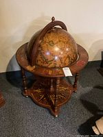 Full view of the globe on wooden stand showing antique map and detailed base artwork