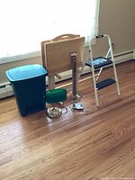 Full view of the lot showing all items together including green plastic garbage can, wooden TV trays on stands, white step stool, and green desk lamp.