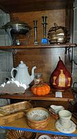 Shelf with various vintage and fall-themed items including metal hot plate, candlesticks, tea pot, pottery, and decorative pumpkins.