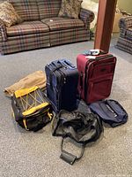 Overall view of all luggage pieces arranged on carpet in living area with plaid couch in background