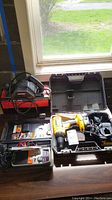 Top view of the cordless drill in case, mobile radio and accessories on table at window