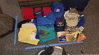 Photo showing the full assortment of Das Awksht Fescht T-shirts, caps, magnets, and rolled blanket laid out on the floor.