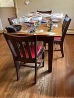 Overall view of wood dining table with four matching chairs, showing table surface and chair design