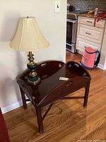 Image of wood butlers table with lamp on top, showing table side and lamp design
