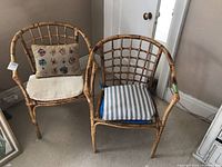 View of two wicker style chairs side by side with cushions.