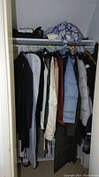 Overview of closet rod showing multiple jackets and folded garments