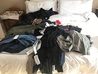 Various clothing items including jackets, sweaters, and pants laid out on a bed.