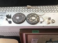 All items in lot: enamel cufflinks, two silver-tone compacts, ring, earring and bangle bracelet arranged on a surface