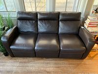 Front view of dark brown leather 3-seater sofa with center fixed seat.