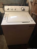 Front view of the GE white washing machine with control panel and lid closed, showing dials and cycle options.