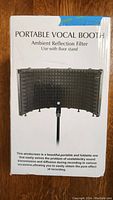 Front box image showing the product name and a photo of the portable vocal booth mounted on a floor stand. Text details the product as a portable, foldable screen to improve sound recording quality.
